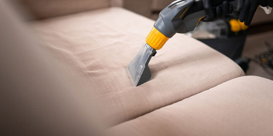cleaning tool being used on beige couch cushions